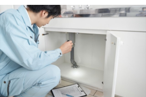 シンク下の修理をしている男性の写真